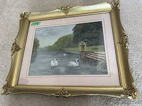 Full view of the framed watercolour painting showing the outdoor lake/swans scene in a decorative gold frame.