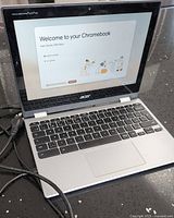 Acer Chromebook Spin 311 open showing keyboard, screen with 'Welcome to your Chromebook' startup page.