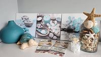 Photo showing three matching 12x12 canvas artworks with spa and nature themes, ceramic turtle figurine, turquoise vase, two packages of peel and stick wall decor, and two glass jars - one filled with potpourri and the other with lace detail.