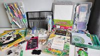 Photo of entire variant shows coloring books, poster boards, markers, shells, scrapbooking supplies, paint brush case, and more items arranged for overview