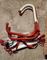Folded fire escape ladder with red and white hooked bars, aluminum rungs, and red nylon straps.