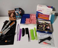 Full view of the hair-care bundle showing the hair straightener, boxed hair dyes, multiple rollers, combs, and clips.