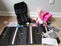 Overview of all included items arranged on floor, showing makeup case, makeup bag, bath bombs, mirrors, brushes, false eyelashes and tools.