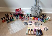 Wide view of all nail polishes, manicure set, nail dryer, nail stickers, and nail care accessories arranged on the floor