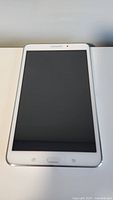 Front view of Samsung Galaxy Tab 4 tablet, white with 8 inch screen, showing Samsung logo and navigation buttons below screen.
