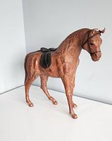 Front-left perspective of the leather horse figurine, showing the full body and saddle.