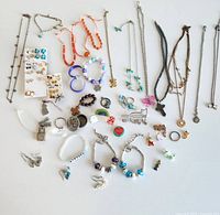 Overview of assorted youth jewelry including necklaces, bracelets, earrings, pins, and rings arranged on a white surface.