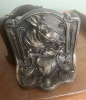 Close-up of one bronze bookend showing detailed horse head in relief with saddle and riding gear motifs on front panel