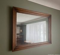 Full view of the large rectangular wall mirror showing the oak wood frame and reflective surface.