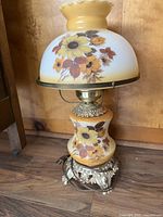 Front view of the electric table lamp showing floral pattern on glass shade and ornate metal base.