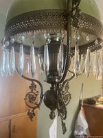 Close-up showing ornate brass metalwork and hanging crystal prisms beneath the glass shade.