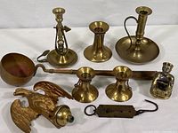 All items together on table showing candlesticks, ladle, eagle topper, incense burner and scale