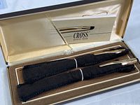 Deluxe presentation box open to show Cross brand ballpoint pen and pencil in black felt sleeves with brand card in lid pocket.