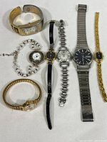 Seven women's watches arranged on flat surface showing bands and faces