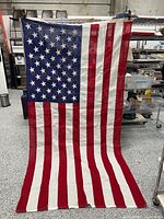 Full view of large U.S. flag hanging vertically, showing red and white stripes and blue canton with white stars.