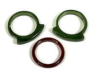 Three polished jade rings: two green with angular protrusions and one smooth red ring.