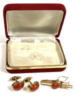 Velvet-covered hinged box open with tie clip and cufflinks displayed in front