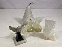 All four carved stone and alabaster figurines together on white surface: pear, eagle, owl, and doves