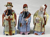 Three Chinese porcelain figurines in a row, showcasing detailed hand painting and colors