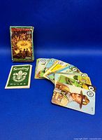 Photo of the original box, rules booklet, and several playing cards fanned out on a blue background