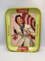 Front view of vintage Coca Cola metal serving tray featuring the Umbrella Girl design, with visible wear and discoloration.