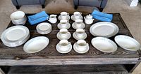 Full set of Royal Doulton 8 piece Floral Garland dinnerware displayed on table with blue linen napkins.