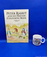 Front cover of the 1985 Peter Rabbit and His Friends colouring book and porcelain mug with Peter Rabbit illustrations