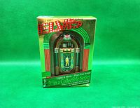 Front of original packaging showing 1997 Carlton Cards Elvis Presley musical jukebox ornament with details about music and lights