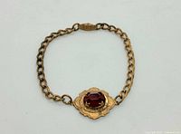Full bracelet showing gold tone chain links and garnet centerpiece with decorative etching and clasp.