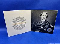 Fold-out collector card opened showing Sir John A. MacDonald's image and embedded $2 coin with text about the story behind the coin
