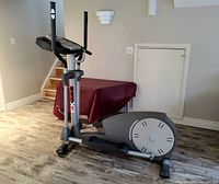 Full view of Sportcraft EX 600 elliptical cross trainer placed on wood flooring in a basement setting.