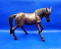 Front and side view of the hand carved wooden horse sculpture with detailed wood grain and texture.