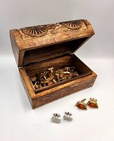 Photo of the carved wooden bicycle box showing the lid open and a variety of cufflinks inside and outside the box.
