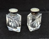 Pair of vintage Birks salt and pepper shakers made of cut crystal glass with mother of pearl and sterling silver caps with visible patina