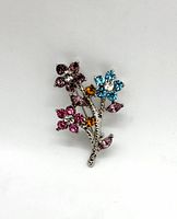 Front view of a vintage silver tone floral bouquet brooch with multi-colored rhinestones showing flowers in purple, pink, blue, orange, and clear.