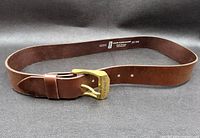 Brown leather L. Strauss belt with brass buckle laid out to show full belt and buckle
