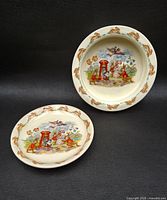Pair of Royal Doulton BUNNYKINS children's dishes showing Postman Bunny scene, including bowl and plate with decorative rims featuring small bunnies.
