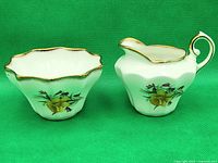 Side view of vintage Salisbury England creamer and sugar bowl set showing daffodil floral pattern and gold trim on white porcelain.