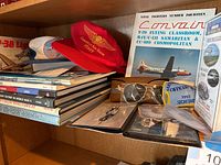 Books, model planes, red hat, sunglasses, and aviation memorabilia arranged on a shelf.