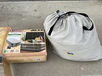 Photo of Coleman ComfortSmart Airbed Twin 18 inch in box next to Serta mattress carry bag.