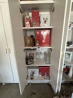 Cabinet overview showing boxed figurines, glass jars, plush bear and ornament boxes on shelves