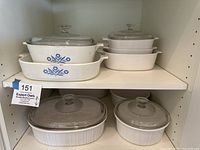 Overall view of 6 Corningware casseroles with cornflower and white French designs on shelf.