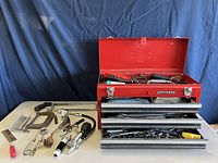 Open red Craftsman toolbox on table with drawers extended and loose tools displayed
