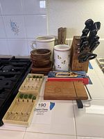 Photo of entire lot showing all wooden and ceramic kitchen items including blocks, bowls, coasters, utensil holders, olive stirrers, cheese cutter and sharpener