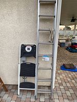 Side view showing both the 16ft extension ladder and the folding step ladder against the wall.