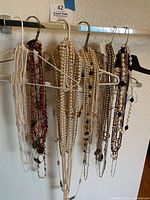 Six hangers with assorted necklaces displayed on a rail