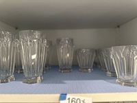 Shelf display of transparent crystal highball and rocks glasses with butterfly design.