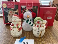 Full set of 5 Lenox snowmen figurines displayed with original boxes behind, showing size and packaging. Includes 3 larger light-up snowmen and 2 smaller porcelain snowmen.