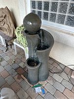 Front view of dark grey textured plastic fountain with large top sphere and two clear spinning LED spheres