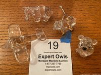 Top-down view of all four Swarovski figurines displayed on a wooden surface including two bears, bear on wheels, and airplane.